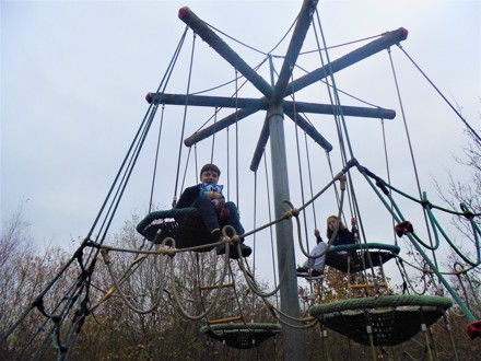 Two student sitting on a climbing frame outside in winter